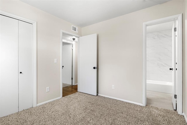 unfurnished bedroom with light colored carpet, ensuite bath, and a closet