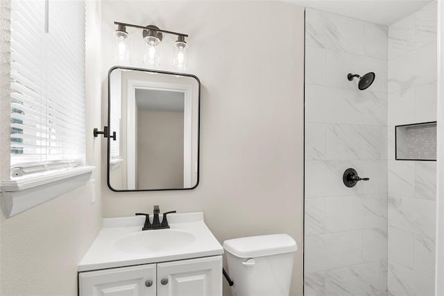 bathroom featuring vanity, tiled shower, and toilet