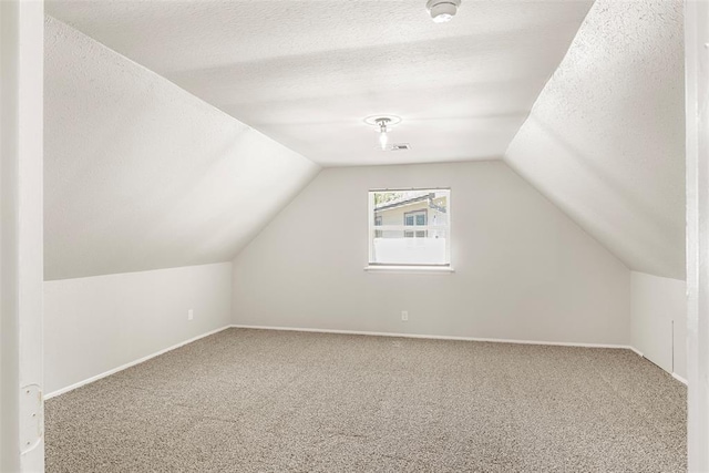 additional living space with lofted ceiling, carpet flooring, and a textured ceiling