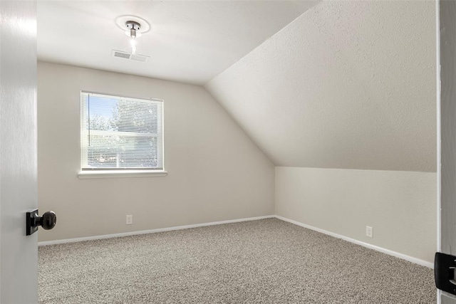 bonus room featuring vaulted ceiling, carpet flooring, and a textured ceiling