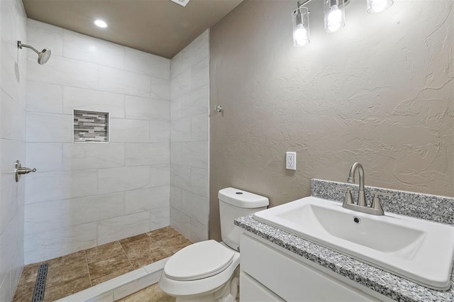 bathroom with vanity, toilet, and a tile shower