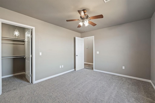 unfurnished bedroom with a spacious closet, a closet, ceiling fan, and carpet