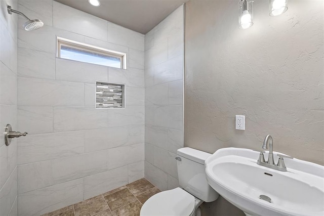 bathroom featuring toilet, sink, and a tile shower