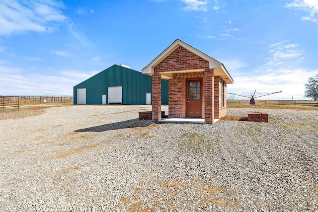 view of front of property with a garage, an outdoor structure, and a rural view