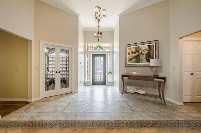 foyer with french doors, ornamental molding, a chandelier, and a high ceiling