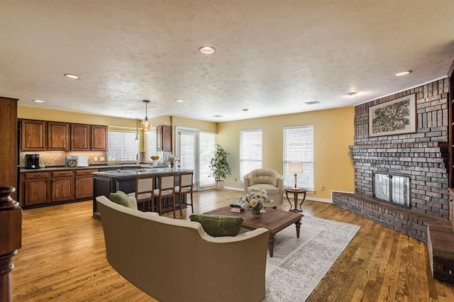 living room with a fireplace, sink, light hardwood / wood-style flooring, and a textured ceiling