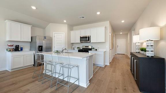 10225 NW 28th St, Yukon, OK 73099 - kitchen featuring a center island with sink, white cabinets, and appliances with stainless steel finishes