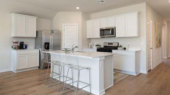 10225 NW 28th St, Yukon, OK 73099 - kitchen with white cabinetry, sink, stainless steel appliances, and a center island with sink