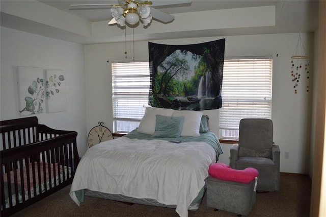 bedroom featuring ceiling fan, a raised ceiling, and carpet floors