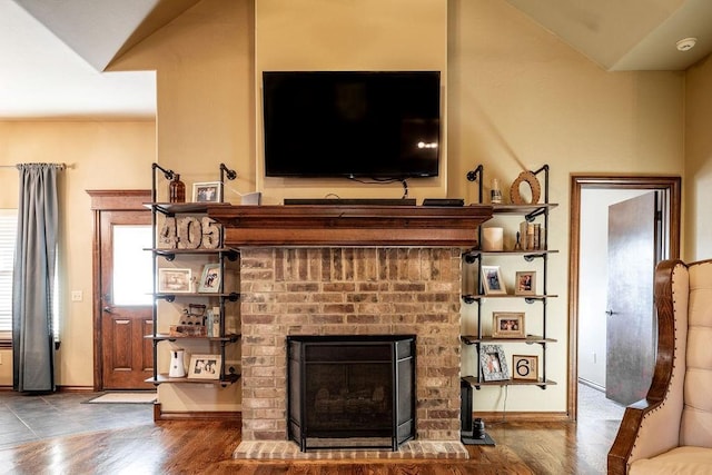 living room with vaulted ceiling, a brick fireplace, and hardwood / wood-style floors