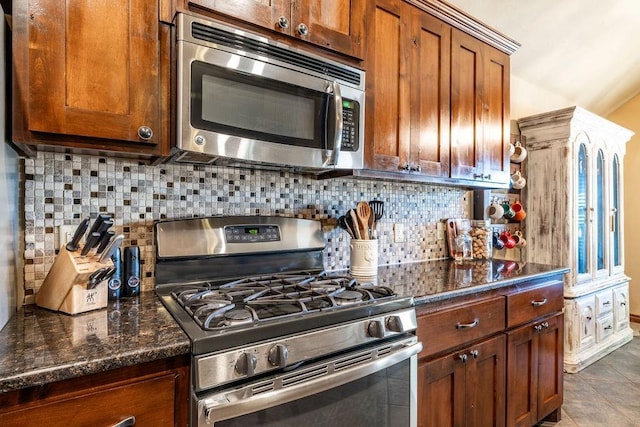 kitchen featuring tile patterned floors, stainless steel appliances, decorative backsplash, and dark stone countertops