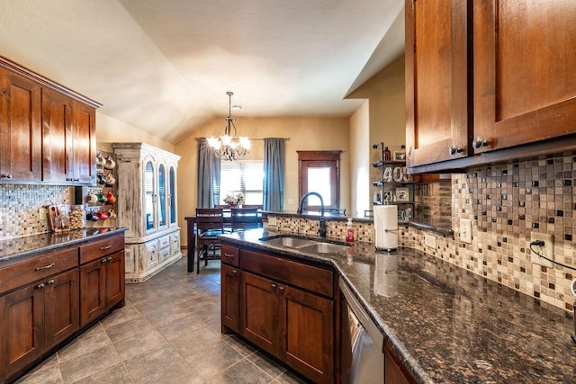 kitchen with pendant lighting, sink, dark stone countertops, backsplash, and an inviting chandelier