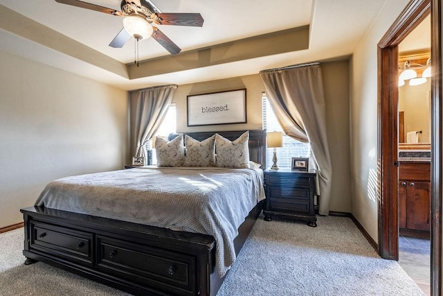 carpeted bedroom with a raised ceiling and ceiling fan