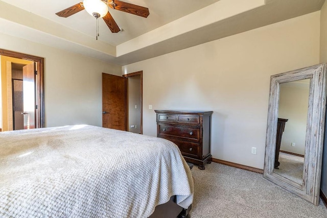 carpeted bedroom featuring a raised ceiling and ceiling fan