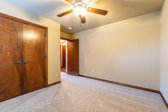 unfurnished bedroom featuring light carpet, a closet, and ceiling fan