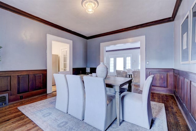 dining space with hardwood / wood-style flooring, ornamental molding, and french doors