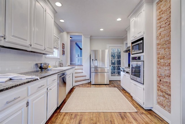 kitchen with light stone counters, sink, white cabinets, and appliances with stainless steel finishes