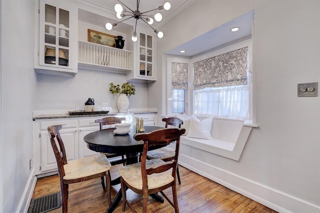 dining area with crown molding, a chandelier, and light wood-type flooring