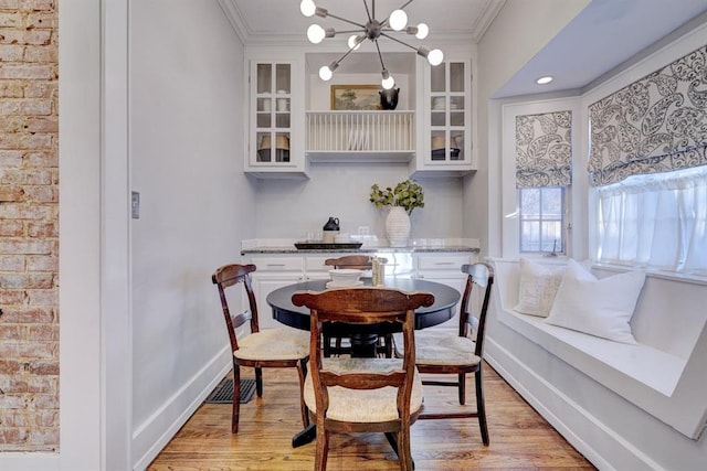 dining space featuring a notable chandelier, ornamental molding, and light wood-type flooring