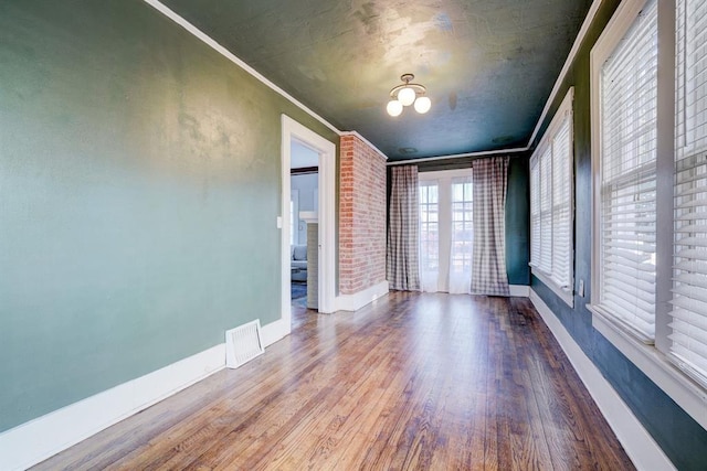 empty room with hardwood / wood-style floors and crown molding