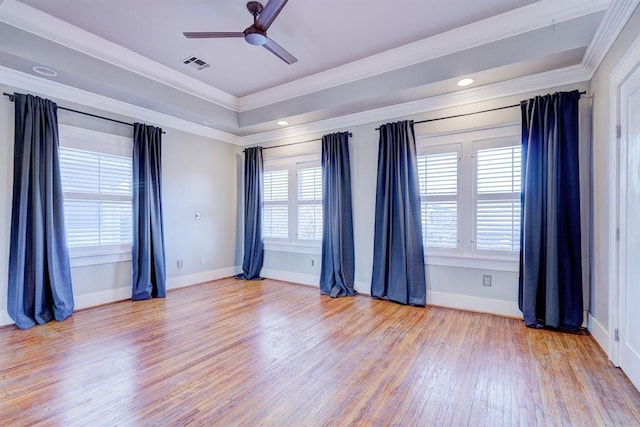 spare room featuring ceiling fan, ornamental molding, a tray ceiling, and light wood-type flooring