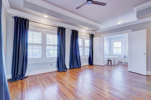 empty room with hardwood / wood-style flooring, ornamental molding, a raised ceiling, and ceiling fan