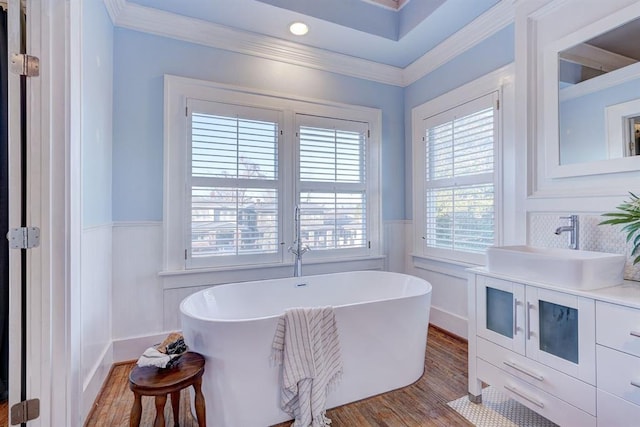 bathroom featuring a bathing tub, wood-type flooring, ornamental molding, and vanity