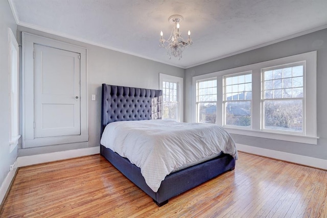 bedroom featuring crown molding, an inviting chandelier, and light hardwood / wood-style flooring