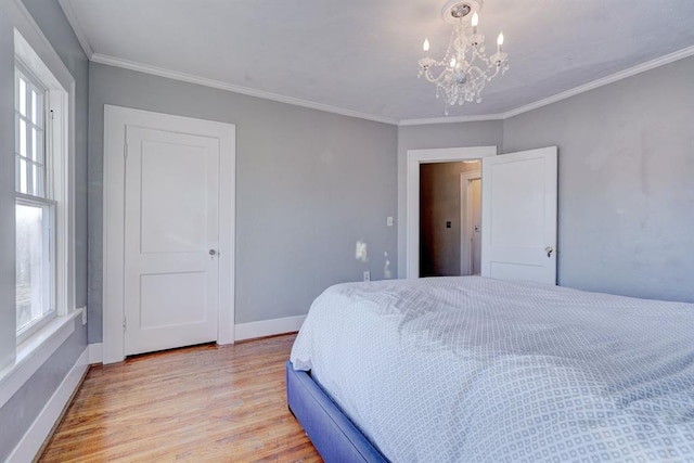 bedroom featuring multiple windows, crown molding, a chandelier, and light wood-type flooring