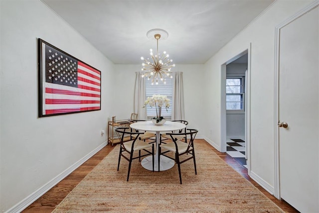 dining space with a chandelier, baseboards, and wood finished floors