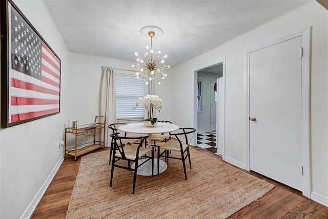 dining space featuring wood finished floors, baseboards, and a chandelier