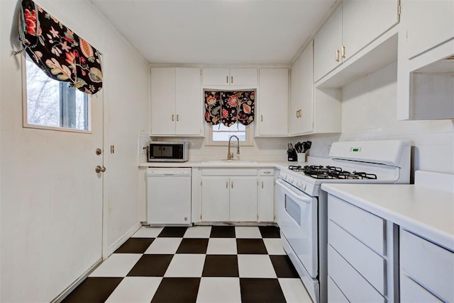 kitchen featuring a sink, white appliances, white cabinets, dark floors, and light countertops