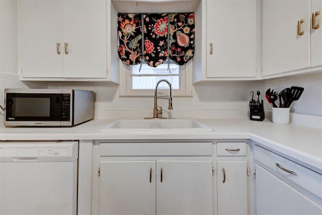 kitchen featuring backsplash, a sink, white cabinets, and white dishwasher