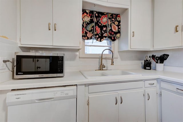 kitchen with stainless steel microwave, white cabinets, dishwasher, and a sink