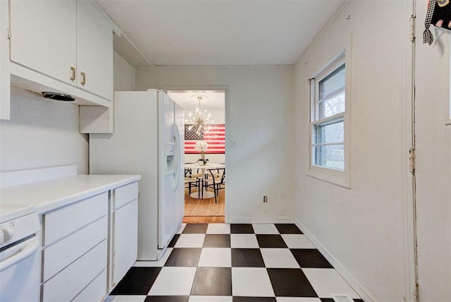 kitchen featuring dark floors, a chandelier, light countertops, stove, and white cabinetry