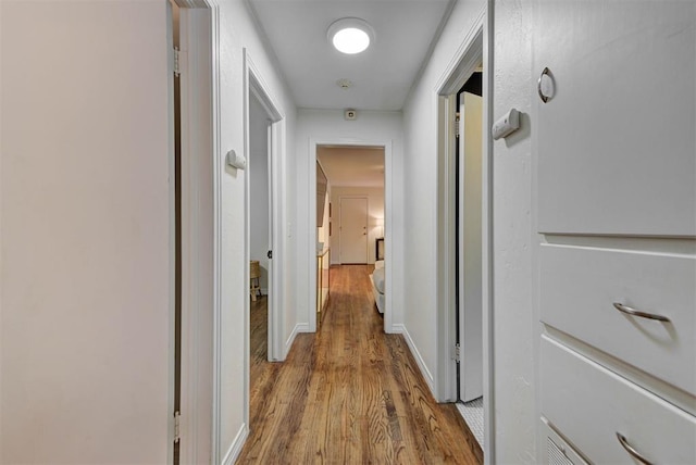 hallway featuring baseboards and wood finished floors