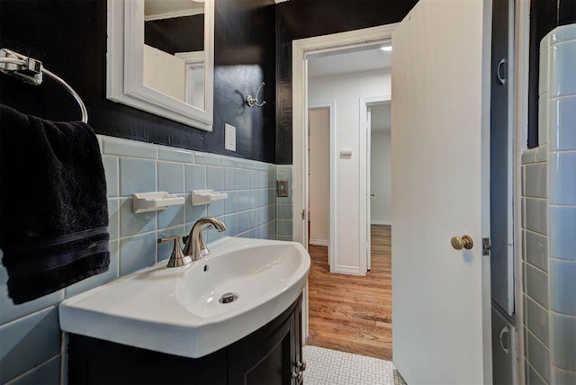 bathroom featuring wood finished floors, tile walls, wainscoting, and vanity