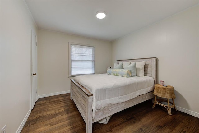 bedroom featuring baseboards, dark wood finished floors, and crown molding