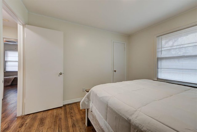 bedroom with wood finished floors, baseboards, and ornamental molding