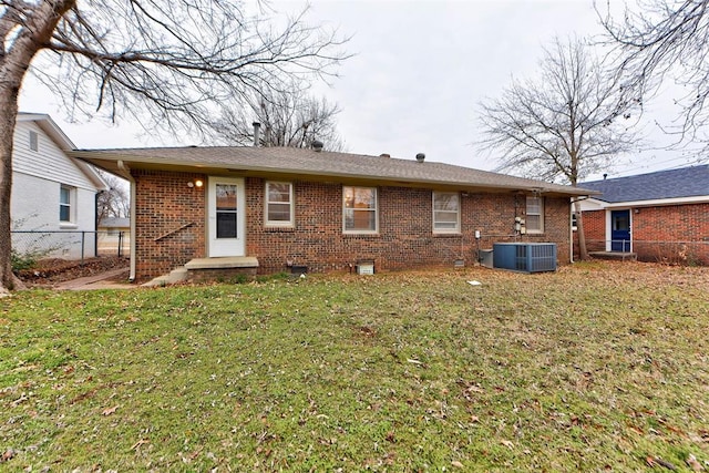 back of house with brick siding, central AC unit, a yard, and fence