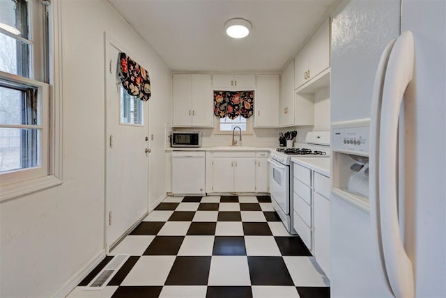 kitchen featuring visible vents, dark floors, light countertops, white appliances, and a sink