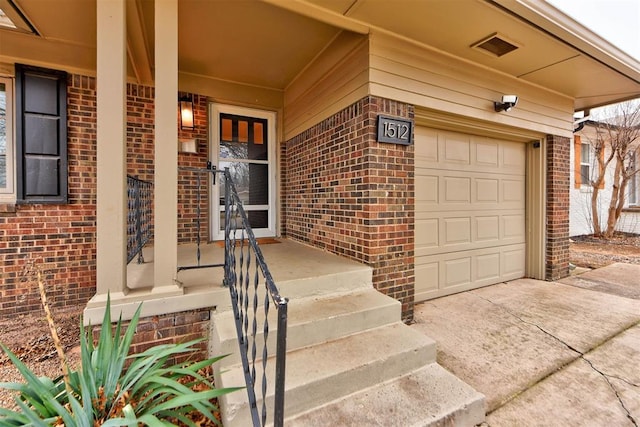 property entrance featuring brick siding, concrete driveway, and a garage