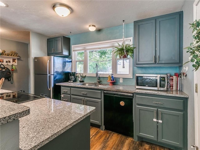 kitchen with light stone counters, sink, stainless steel appliances, and dark hardwood / wood-style floors