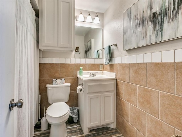 bathroom featuring vanity, toilet, and tile walls