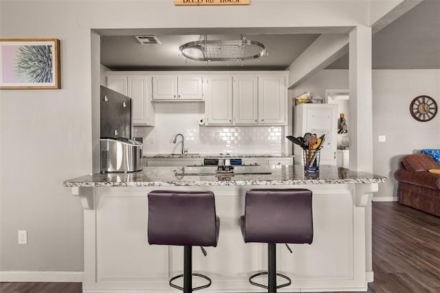 kitchen with light stone countertops, a breakfast bar, and white cabinets