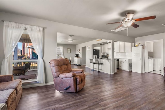 living room with ceiling fan, washing machine and clothes dryer, and dark hardwood / wood-style flooring