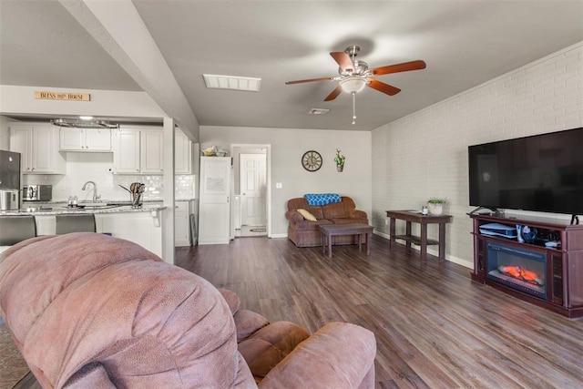 living room featuring ceiling fan, brick wall, and dark hardwood / wood-style flooring