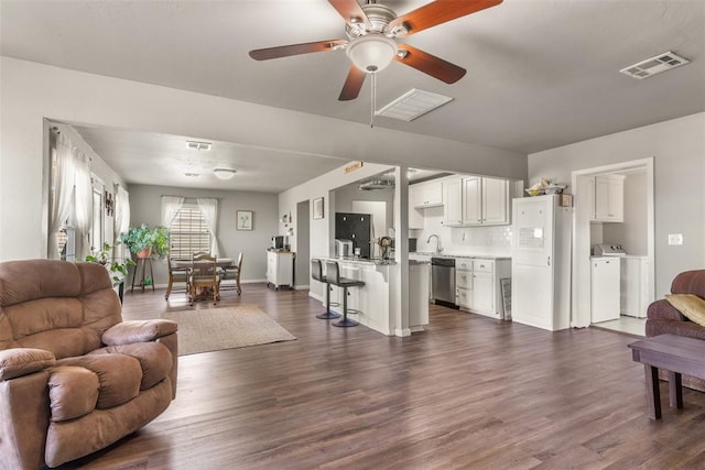 living room featuring ceiling fan, dark hardwood / wood-style flooring, sink, and washer and dryer