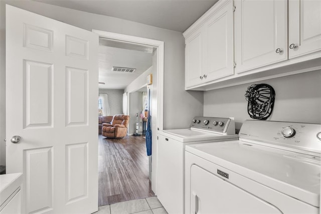 laundry area with cabinets, washing machine and dryer, and light tile patterned floors