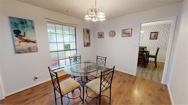 dining area with wood-type flooring, a textured ceiling, and a notable chandelier